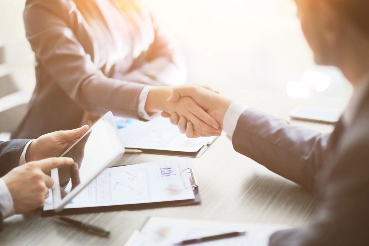 Business handshake over documents and tablet