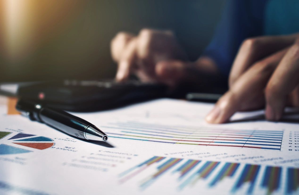 Pen on financial charts with hands
