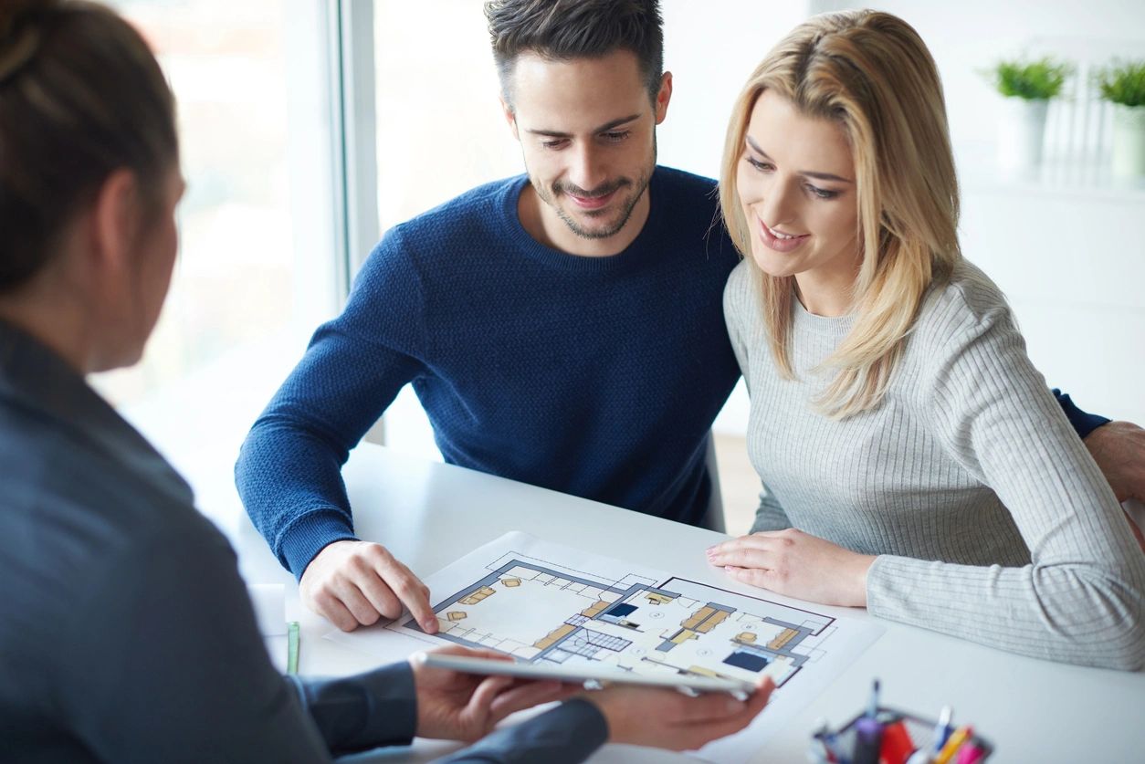 Couple reviewing house floor plan with agent